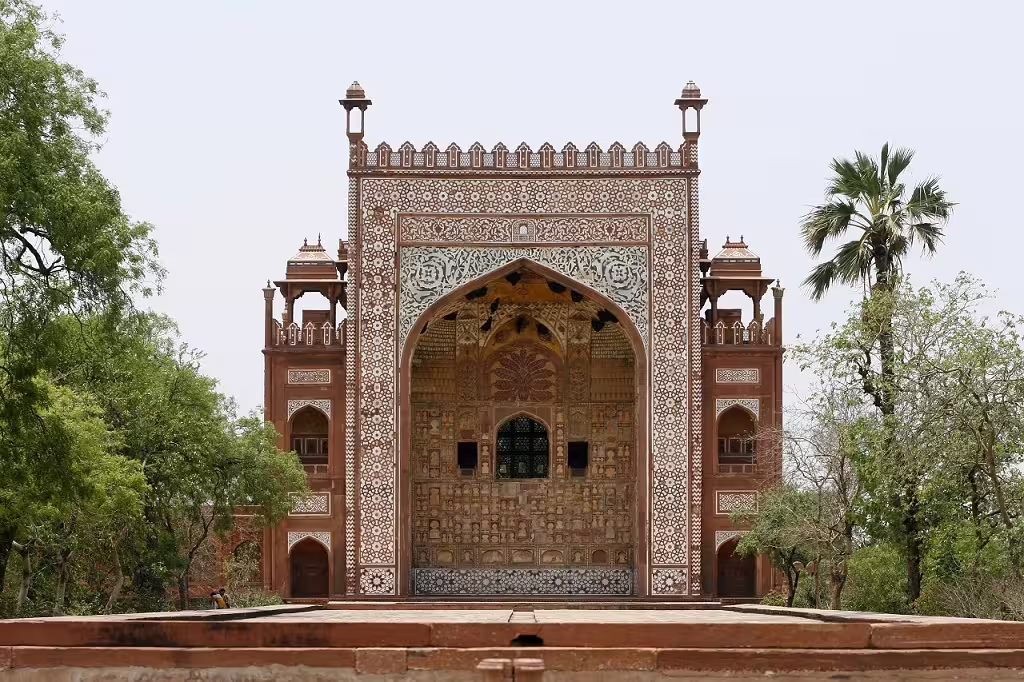 Intricate Mughal architecture of a historic North Indian monument surrounded by lush greenery.