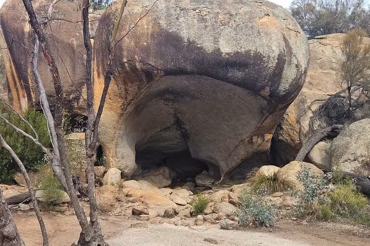 Entrance to Mulka's Cave featuring large rock formations and native vegetation, a highlight of the day tour.