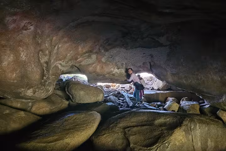 Explorer inside Mulka's Cave surrounded by ancient rock formations on a guided day tour in Western Australia.