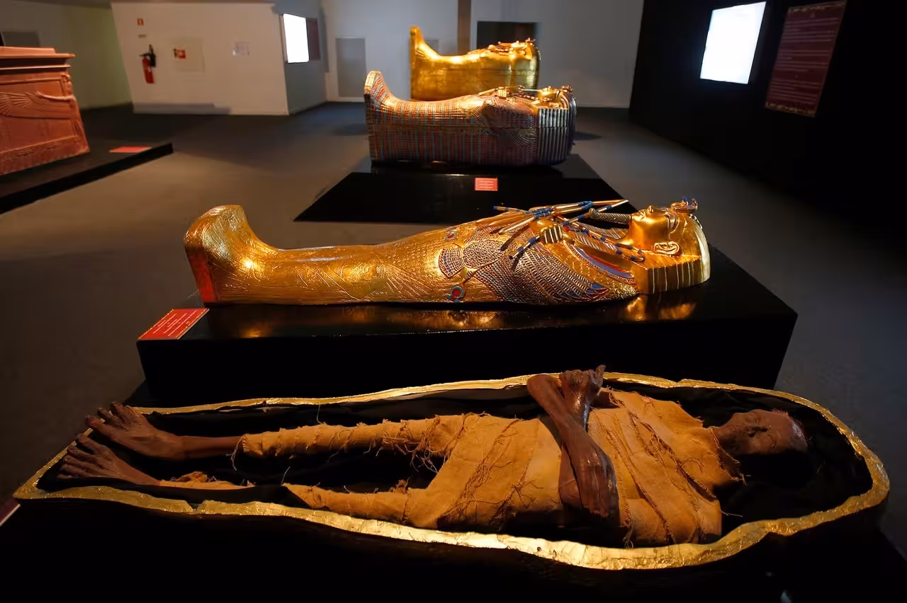 Mummification Museum Luxor display with gilded coffins and wrapped mummy, featured on the Luxor museum tour