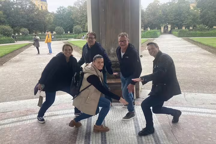 Group posing at a Munich park landmark on a self-guided scavenger hunt tour, exploring sights and hidden gems