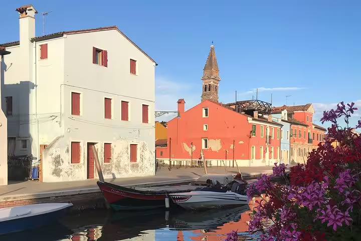 Charming view of colorful houses and boats in a canal on a sunny day in Burano, ideal for a Murano Burano Torcello limo boat tour.