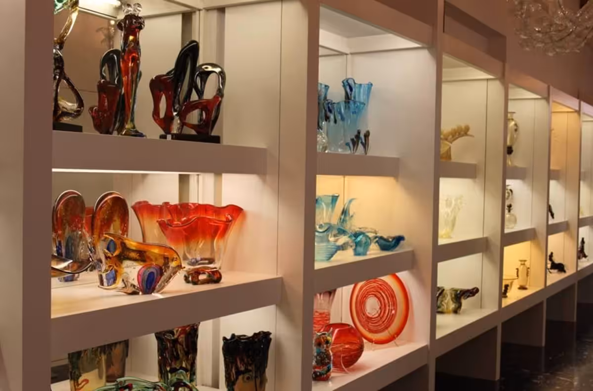 Colorful Murano glass art pieces displayed on shelves, highlighting exquisite craftsmanship on the Grand Tour.
