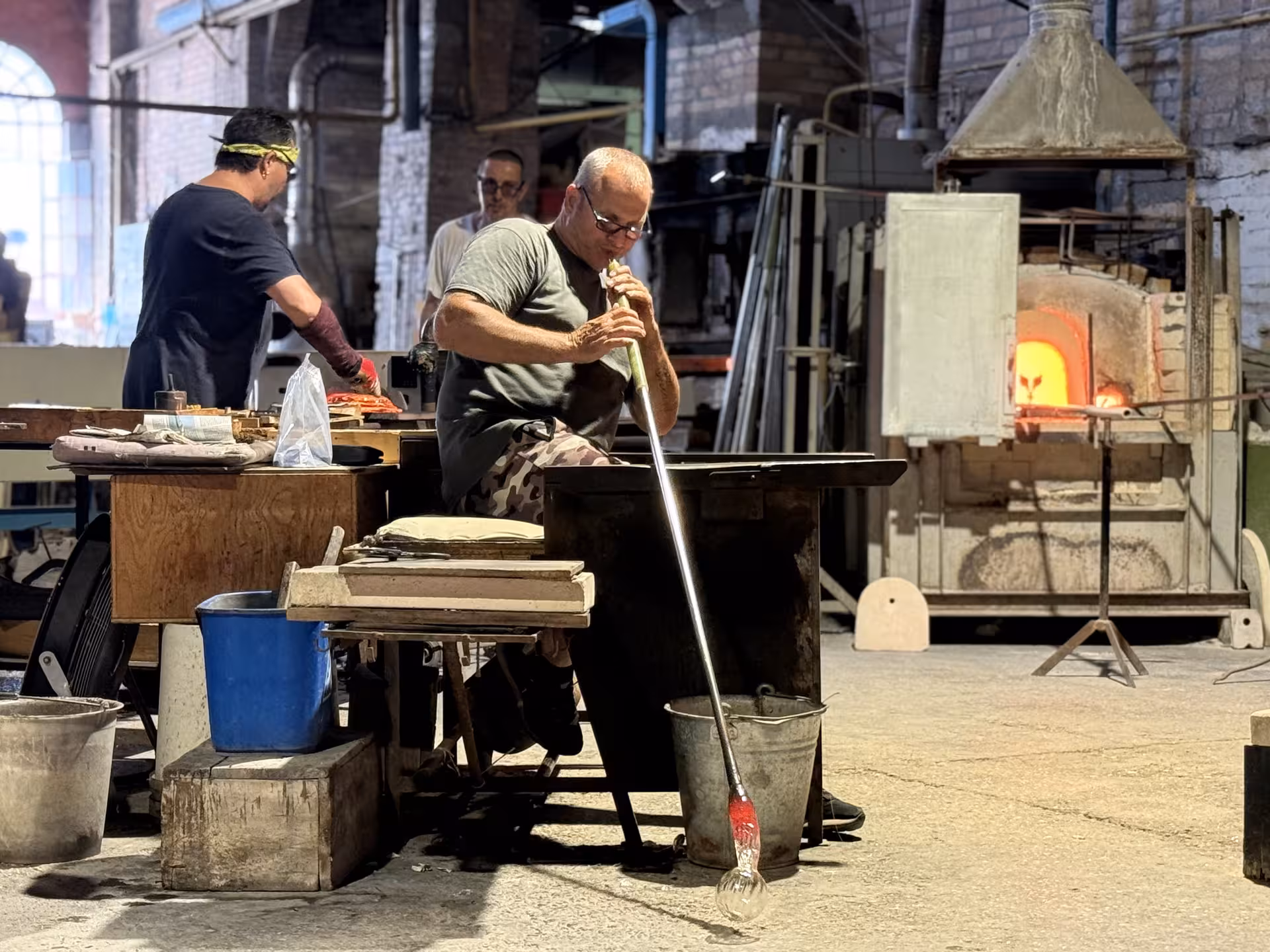 Artisan crafting delicate Murano glass with traditional techniques in a workshop on the Lagoon Cruise tour.