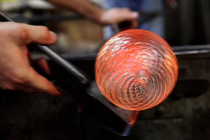 Artisan crafting Murano glass with glowing molten orb during Grand Canal and Murano tour from San Marco Square.