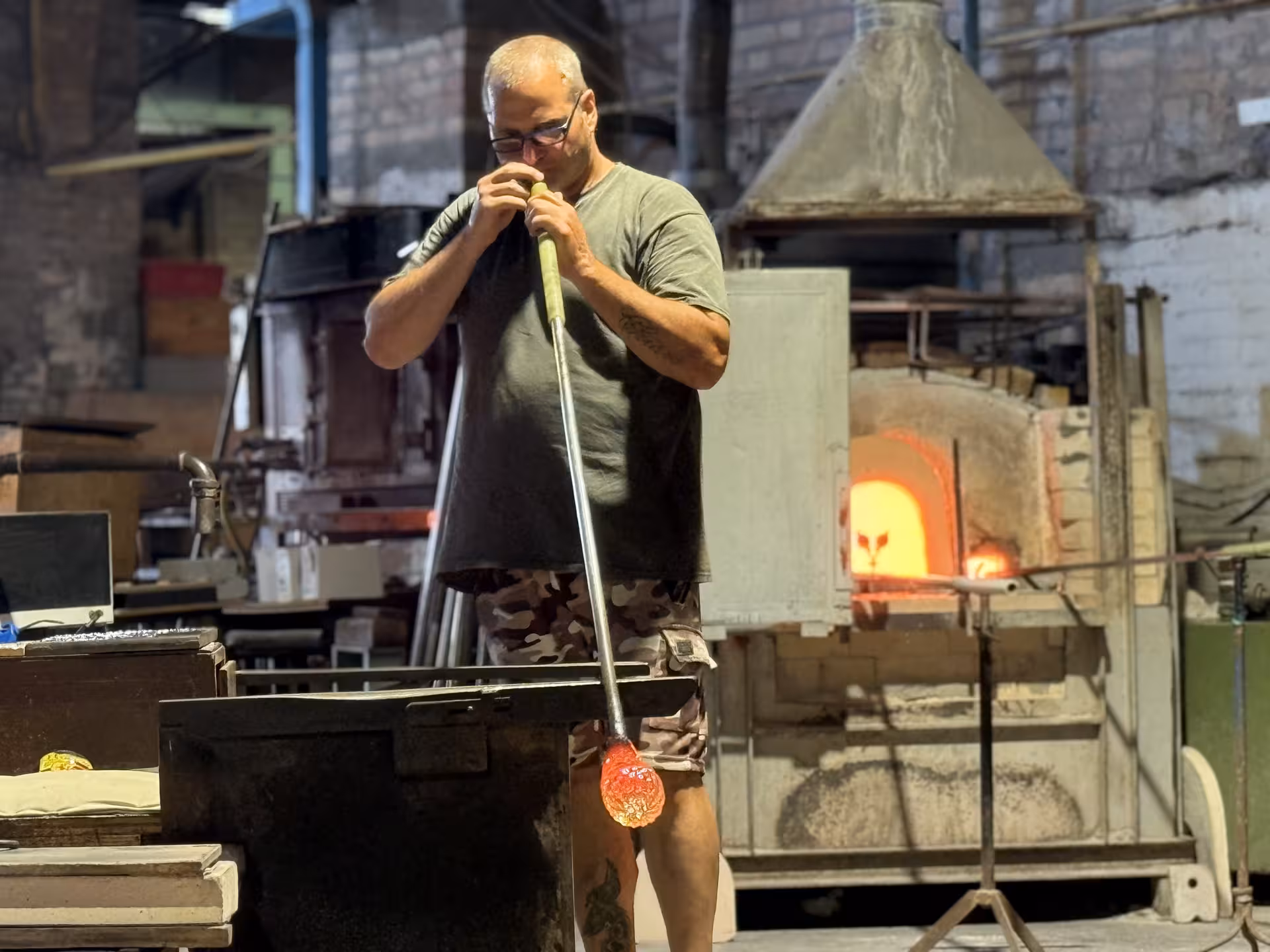 Skilled artisan crafting Murano glass in a hot furnace, showcasing the artistry of Venice glassblowing traditions.