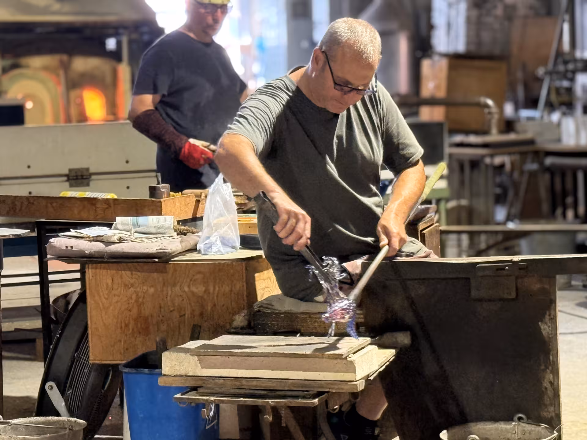 Artisan crafting intricate Murano glass piece in a traditional Venetian workshop, part of guided speedboat tour.