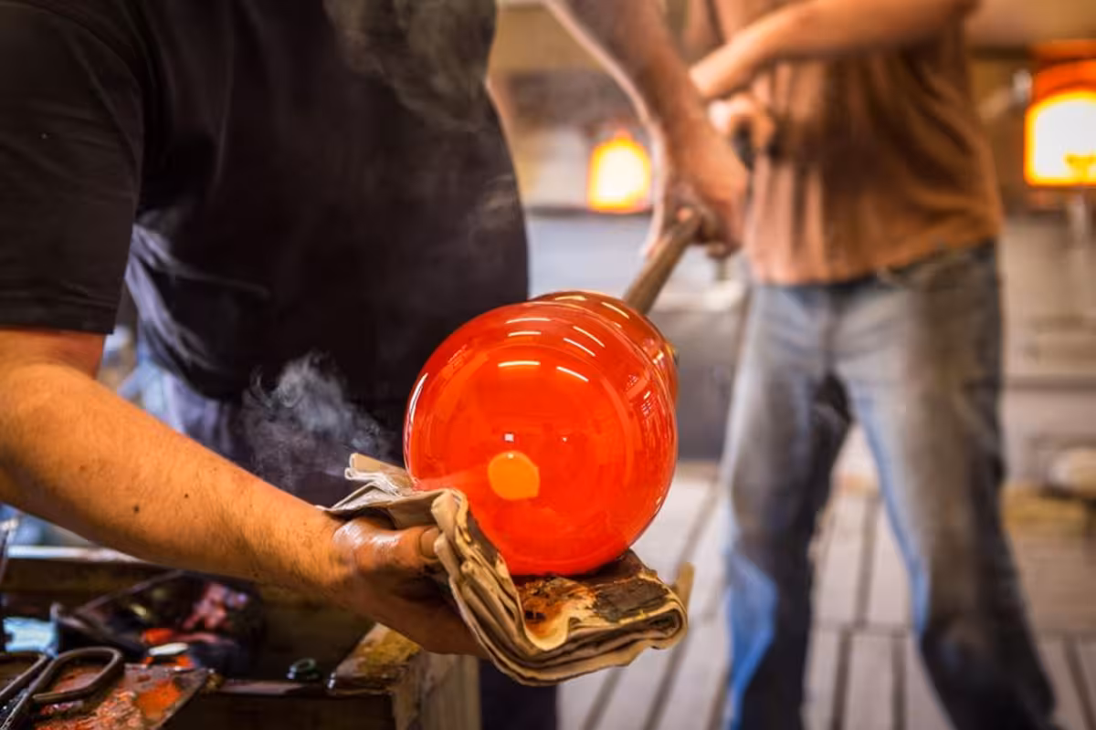 Artisan crafting vibrant red Murano glass piece during Grand Tour experience in Venice.