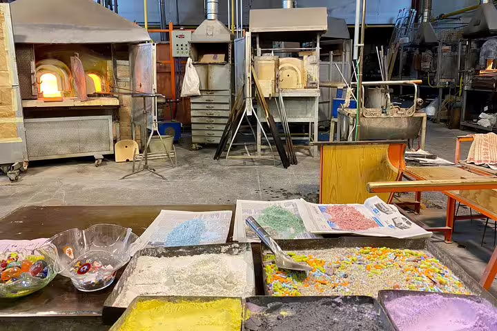 Inside a Murano glass factory showcasing colorful raw materials and ovens used for traditional glassmaking.