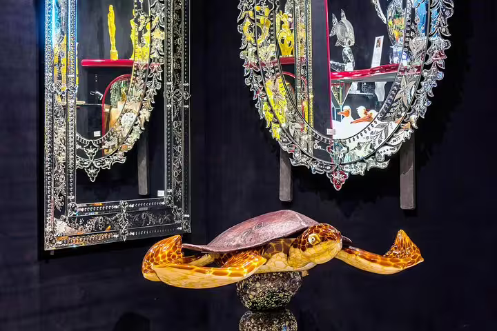 Intricate Murano glass turtle sculpture and ornate mirrors in a Venetian art gallery on LimoBoat tour.