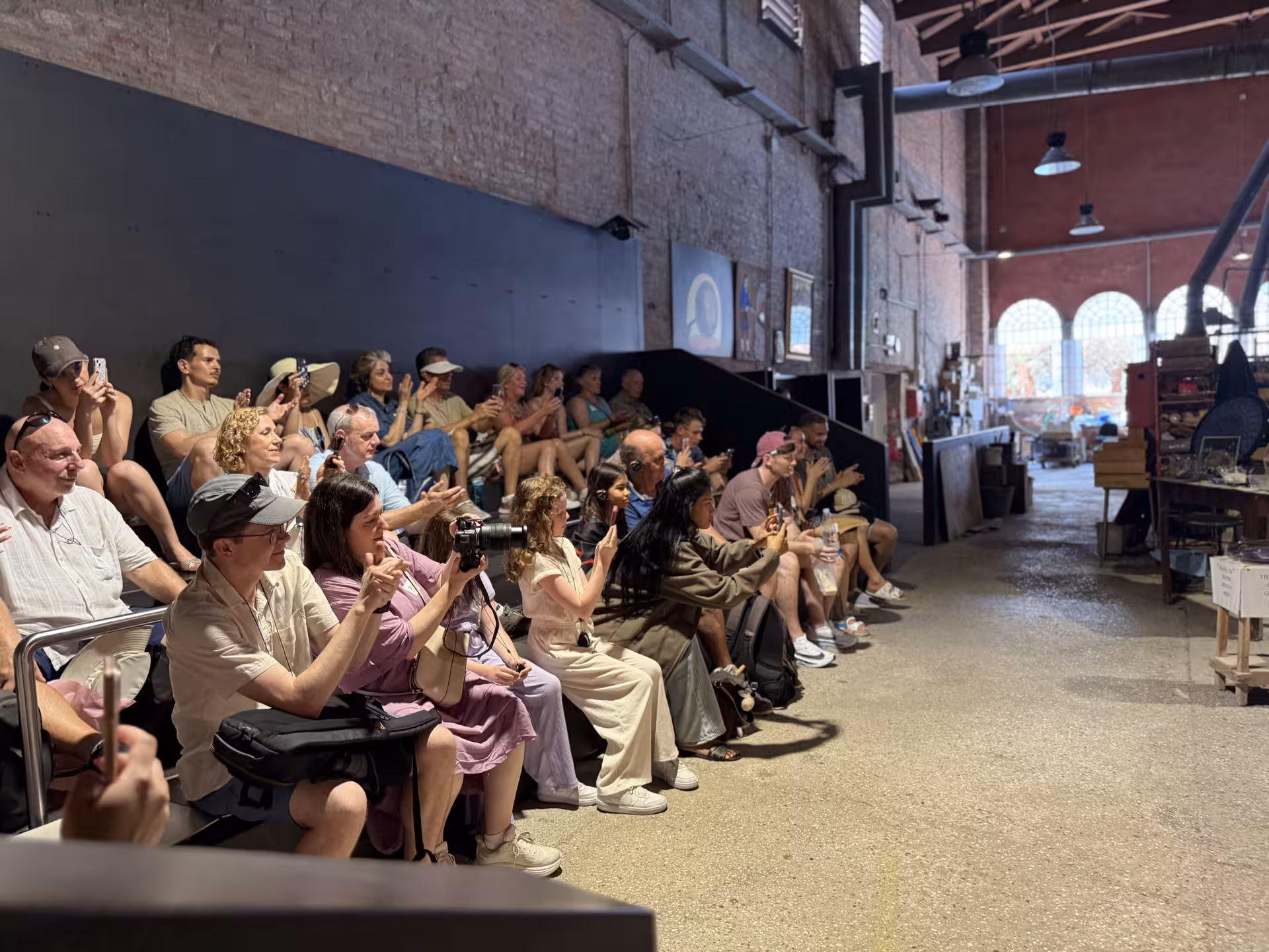 Tourists enjoy a glassmaking demonstration in a Murano workshop during a Venice Islands guided cruise.