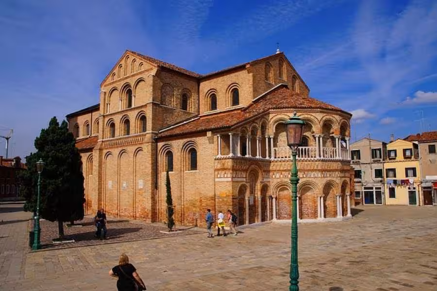 Scenic view of the historic Basilica di Santa Maria e San Donato on Murano Island under a clear blue sky.