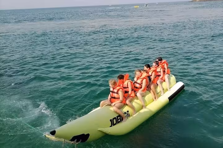 Guests in life jackets riding banana boat in Musandam, fun add-on during fishing and snorkeling lunch cruise