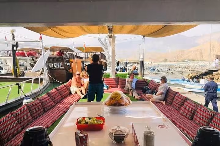 Traditional dhow boat seating with buffet lunch setup at Khasab harbor for Musandam cruise, snorkeling and fishing