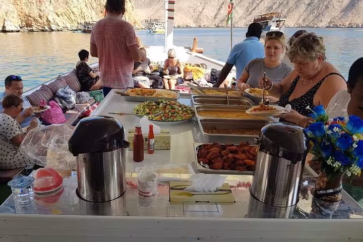 Buffet lunch served onboard Musandam dhow cruise, guests dining after fishing and snorkeling in the fjords