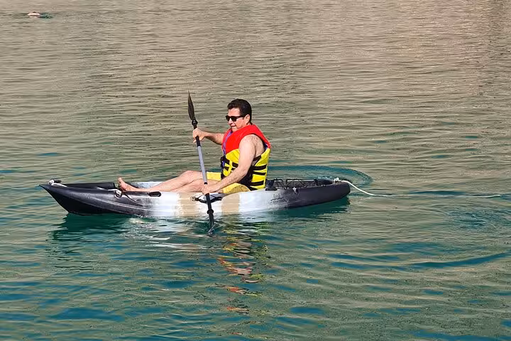 Tourist kayaking on calm Musandam waters during dhow cruise with fishing, snorkeling and lunch included