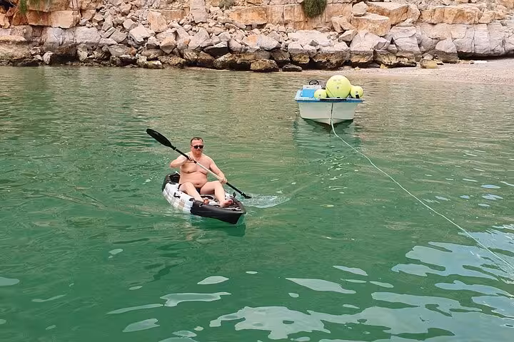 Traveler kayaking in Musandam fjords near rocky coast during Khasab boat trip with snorkeling, fishing and lunch