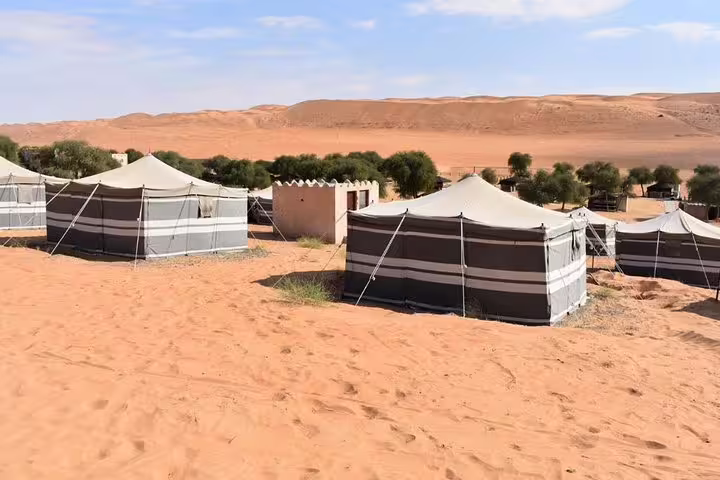 Traditional desert tents set against the sandy landscape of Wahiba Sands, offering a unique Muscat 4x4 adventure.