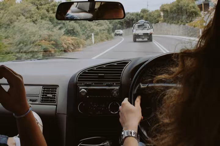 Comfortable private car driving through green Omani countryside, showcasing scenic Muscat Airport transfer journey