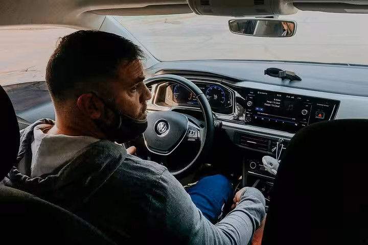 Professional driver in modern sedan ready to provide reliable Muscat Airport hotel transfer with comfortable in-car amenities