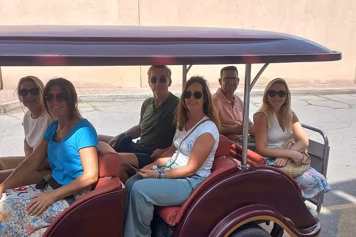 Group of friends riding an open electric buggy through historic streets on a guided half-day Muscat City sightseeing tour