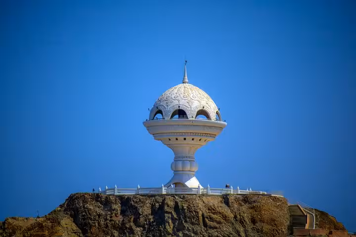 Iconic incense burner monument atop Riyam Park hill under clear blue skies, scenic viewpoint on a guided half-day Muscat city tour