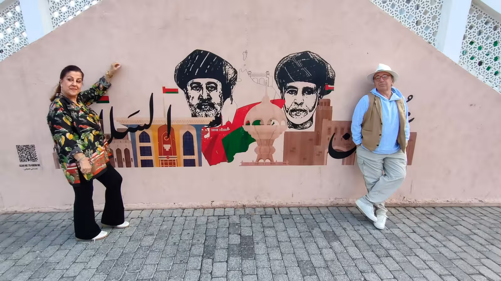 Tourists posing by colorful Muscat street art and Omani heritage mural during a private half day Muscat city sightseeing