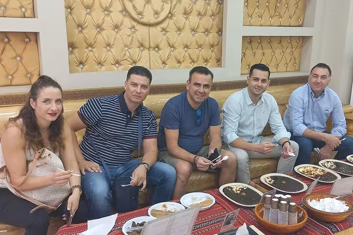 Tourists enjoy traditional Omani sweets and coffee in a local café during a Half-Day Muscat City tour cultural experience