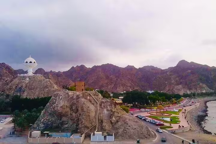 Scenic panorama of Muscat's landscape featuring mountains, coastline, and the famous incense burner landmark.