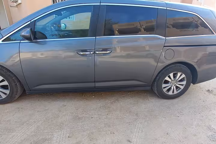 Side view of spacious gray minivan used for Muscat to Dubai private transfer, offering door to door travel service