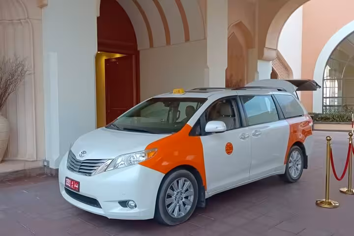 Comfortable Muscat to Dubai private transfer taxi waiting at a luxury hotel entrance, ideal for airport and city pickups