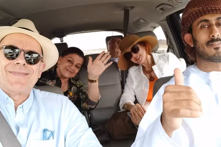 Happy tourists ride in a private taxi with local driver during Muscat evening sightseeing tour, enjoying comfortable city travel