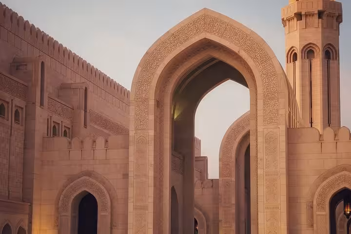 Close-up of ornate stone archways and minaret at Muscat Grand Mosque, showcasing Islamic architecture on a private city tour
