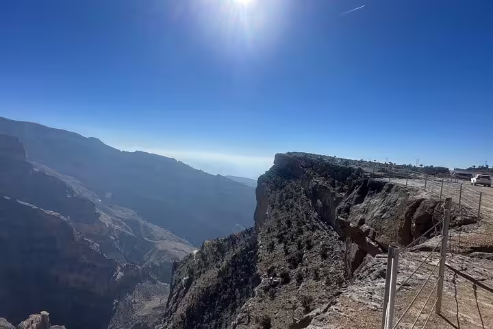 Scenic view from Jabal Al Akhdar with rugged cliffs and expansive valleys under a bright blue sky in Oman.
