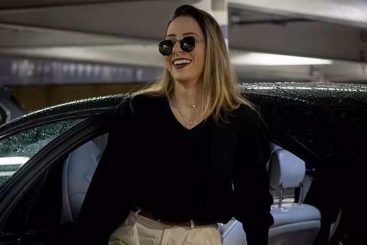 Smiling traveler stepping from luxury car, enjoying Muscat private chauffeur transfer service in covered parking area