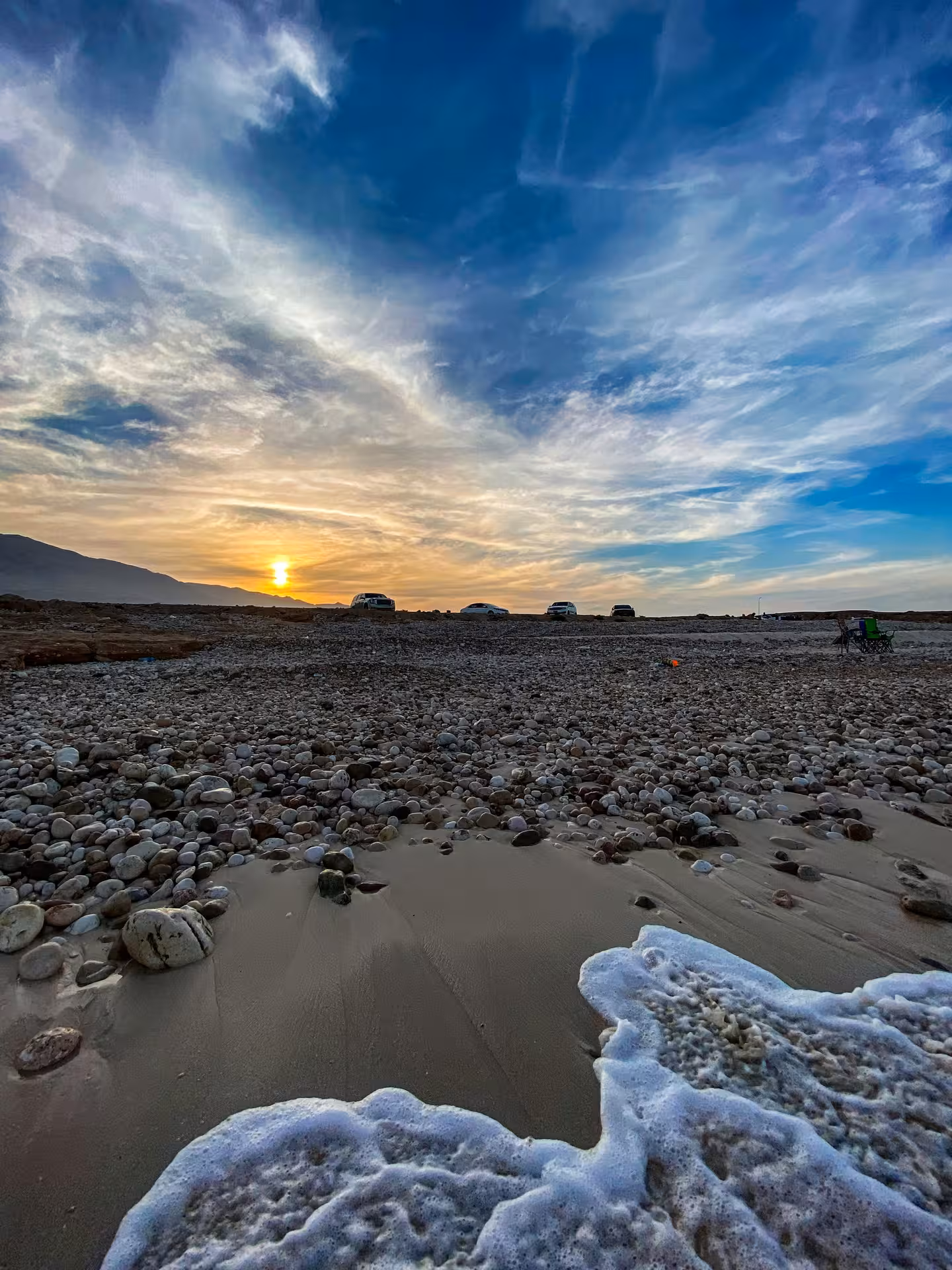 Sunset over a rocky Oman beach near Ras Al Jinz, 4x4 jeeps parked for turtle watching on a Muscat desert and coast tour