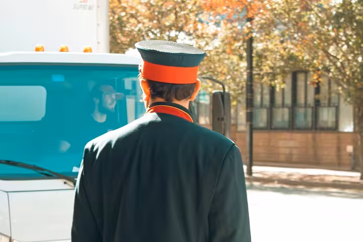 Uniformed chauffeur waiting curbside for Muscat private transfer service, ready for hotel pickup and city transport
