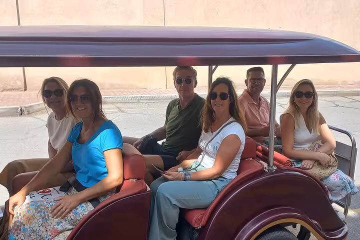 Group of friends riding in an open electric buggy during Muscat private sightseeing tour with hotel pickup and transport