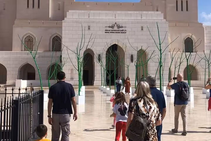 Tourists walk toward Muscat’s Royal Opera House entrance during a guided half day city tour to Bimmah Sinkhole