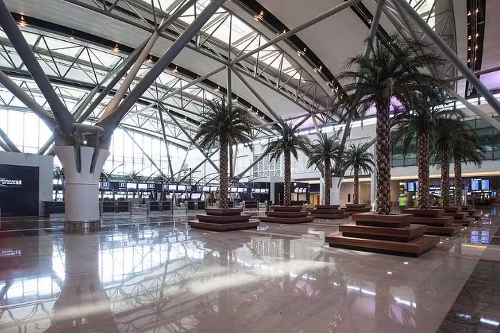 Spacious interior of Muscat Seeb International Airport with modern architecture and palm trees, ideal for private transfers.