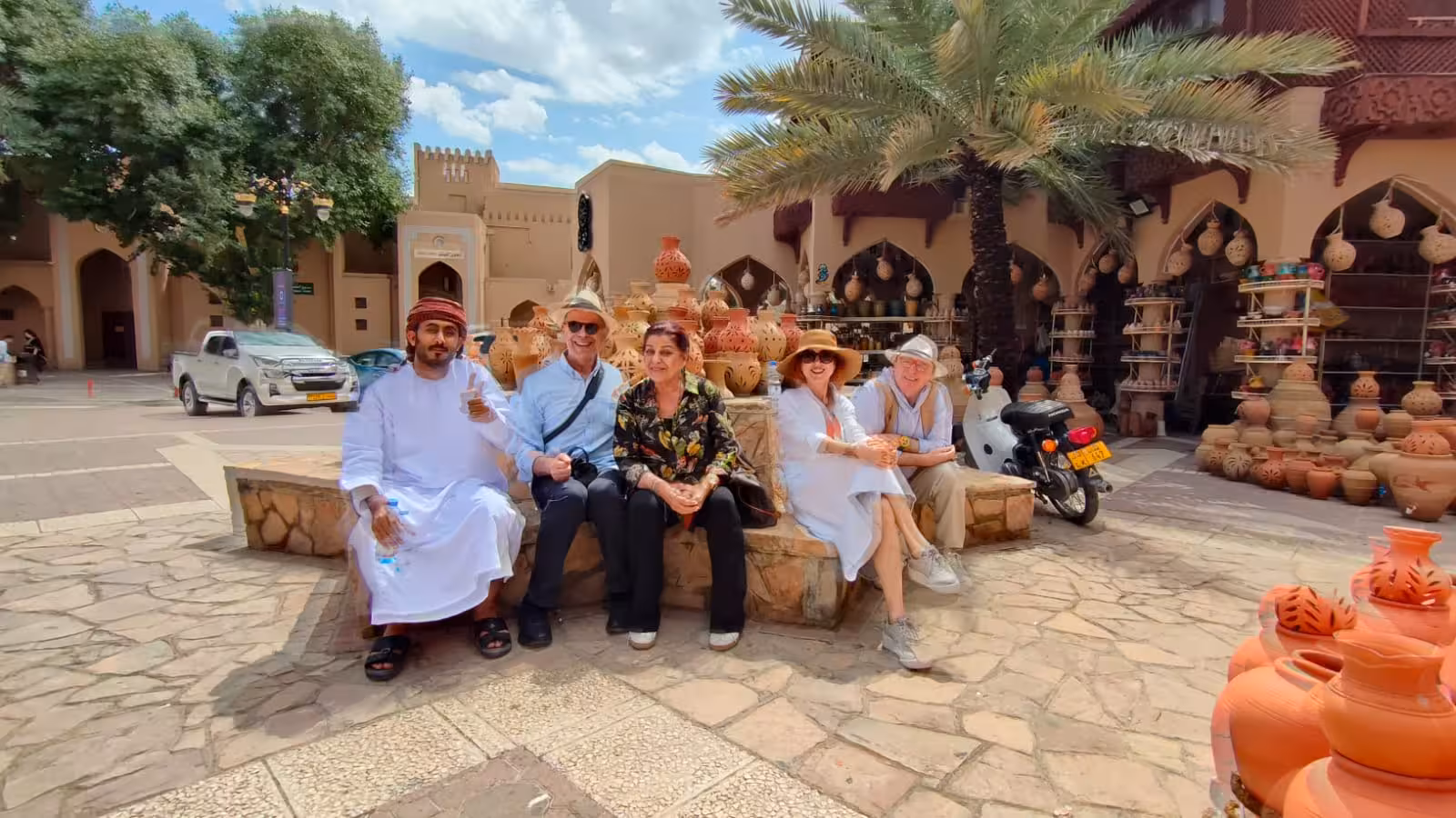 Small group with local guide relaxing by clay pots at a traditional Muscat souq on a private half day city tour in Oman