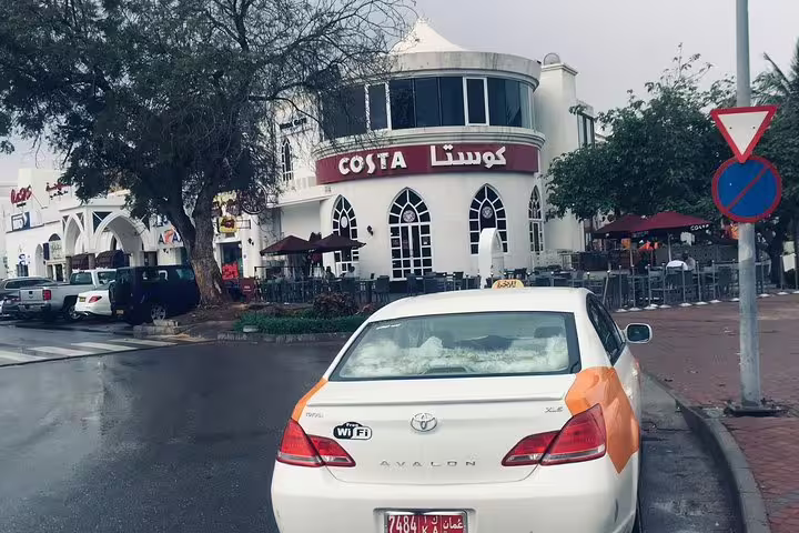 Taxi in front of a popular café in Muscat, emphasizing the city's vibrant local culture and dining scene.