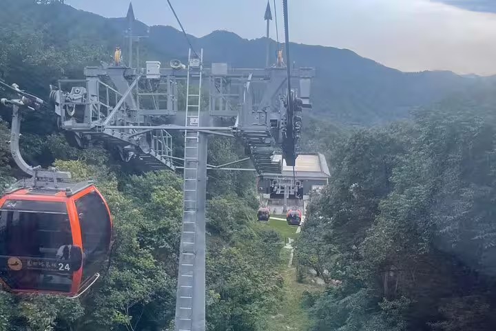 Close-up of vibrant cable cars approaching a station amidst green hills on Mutianyu Great Wall private day excursion.