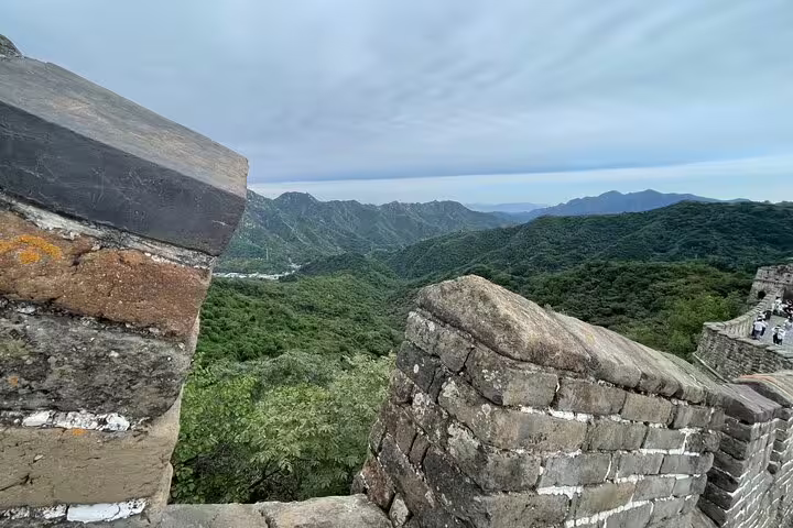 Scenic view of the Mutianyu Great Wall surrounded by lush green mountains on a private day trip with English-speaking driver.