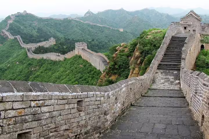 Scenic pathway along the Mutianyu Great Wall, showcasing historic stone steps and verdant mountain terrain.