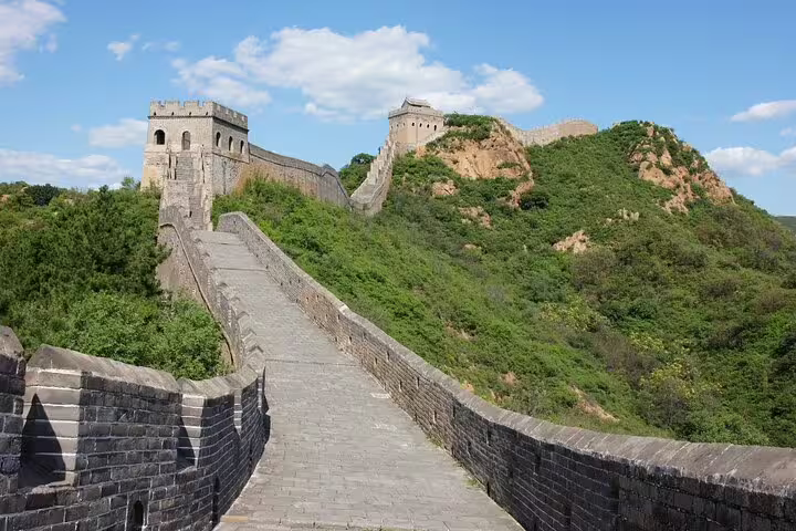 Sunny day at the Mutianyu Great Wall with watchtowers and green hills under a bright blue sky.