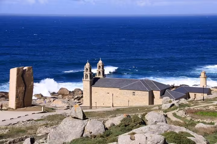 Scenic view of the historic church by the ocean in Muxia, highlighting Costa da Morte's rugged coastline charm.