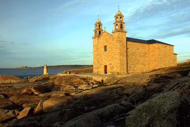 Historic stone church at Muxia illuminated by sunset, part of the Finisterre and Cabo Vilan tour with boat cruise.