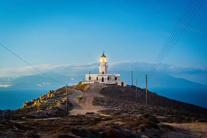 Scenic view of the Mykonos Armenistis Lighthouse at dusk, overlooking the Aegean Sea, perfect for countryside and tasting tours.