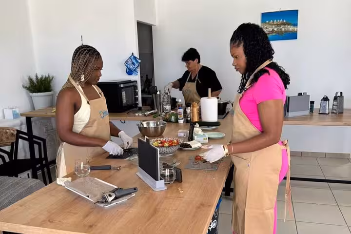 Guests prep fresh ingredients at a small group Mykonian cooking class in a modern Mykonos kitchen